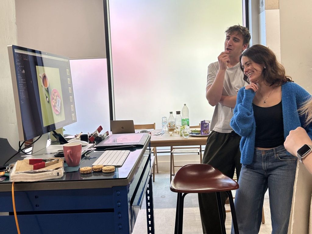 Florence standing with a colleague, assessing their work on a computer screen.