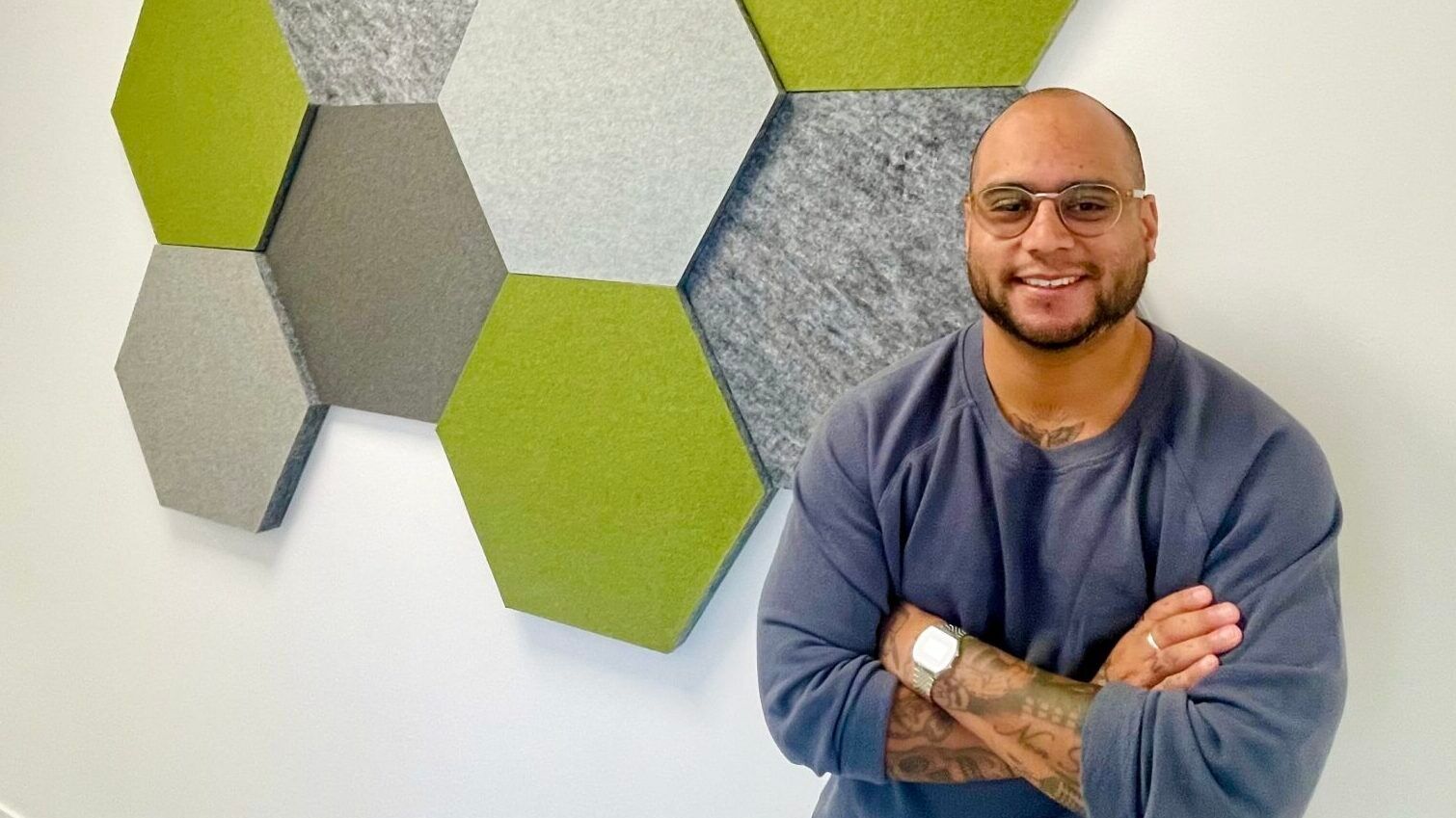 Eddie Sjöberg leans against the wall at his office, decorated with green soundproof pentagonal tiles.