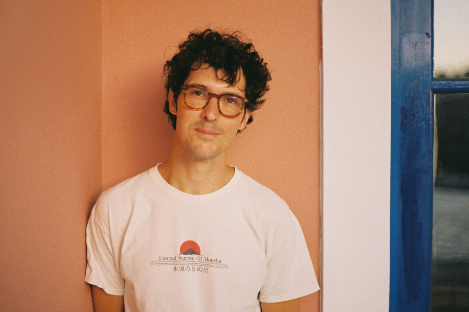 Stefan Vucicevic, a Brand Strategy student, leans against an orange wall and smiles at the camera.