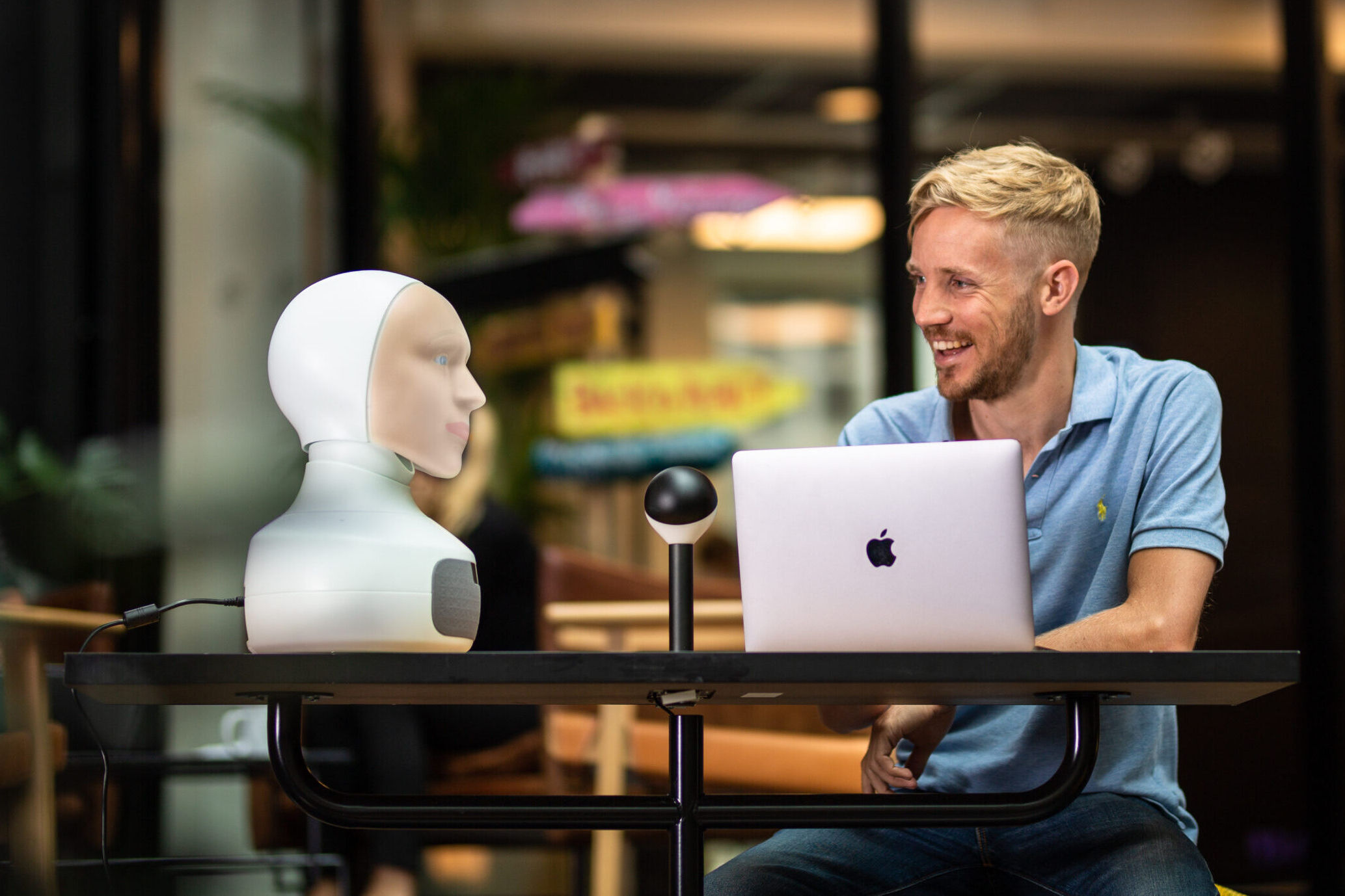 An image of Chris facing a robot from Furhat Robotics.
