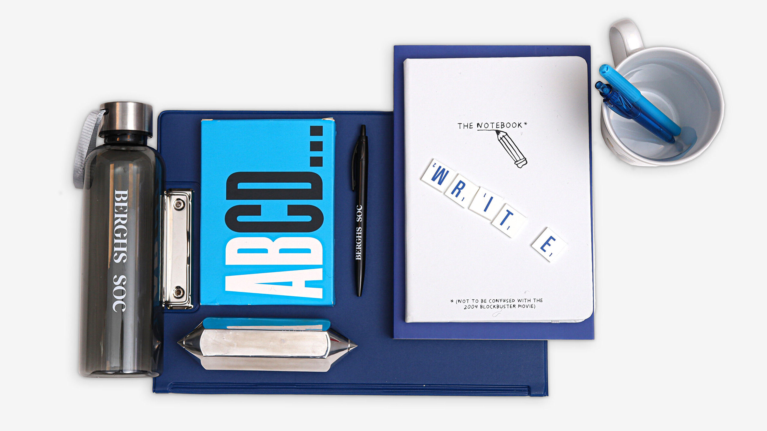 A composition with blue pens, a bottle, a notebook, and an international award. The picture represents tools and ideas related to the course "Content Design and UX Writing" at Berghs School of Communication