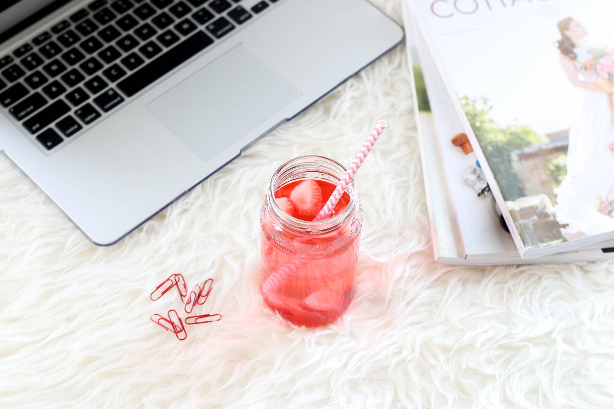 Laptop, paperclips, a summery drink and magazines.