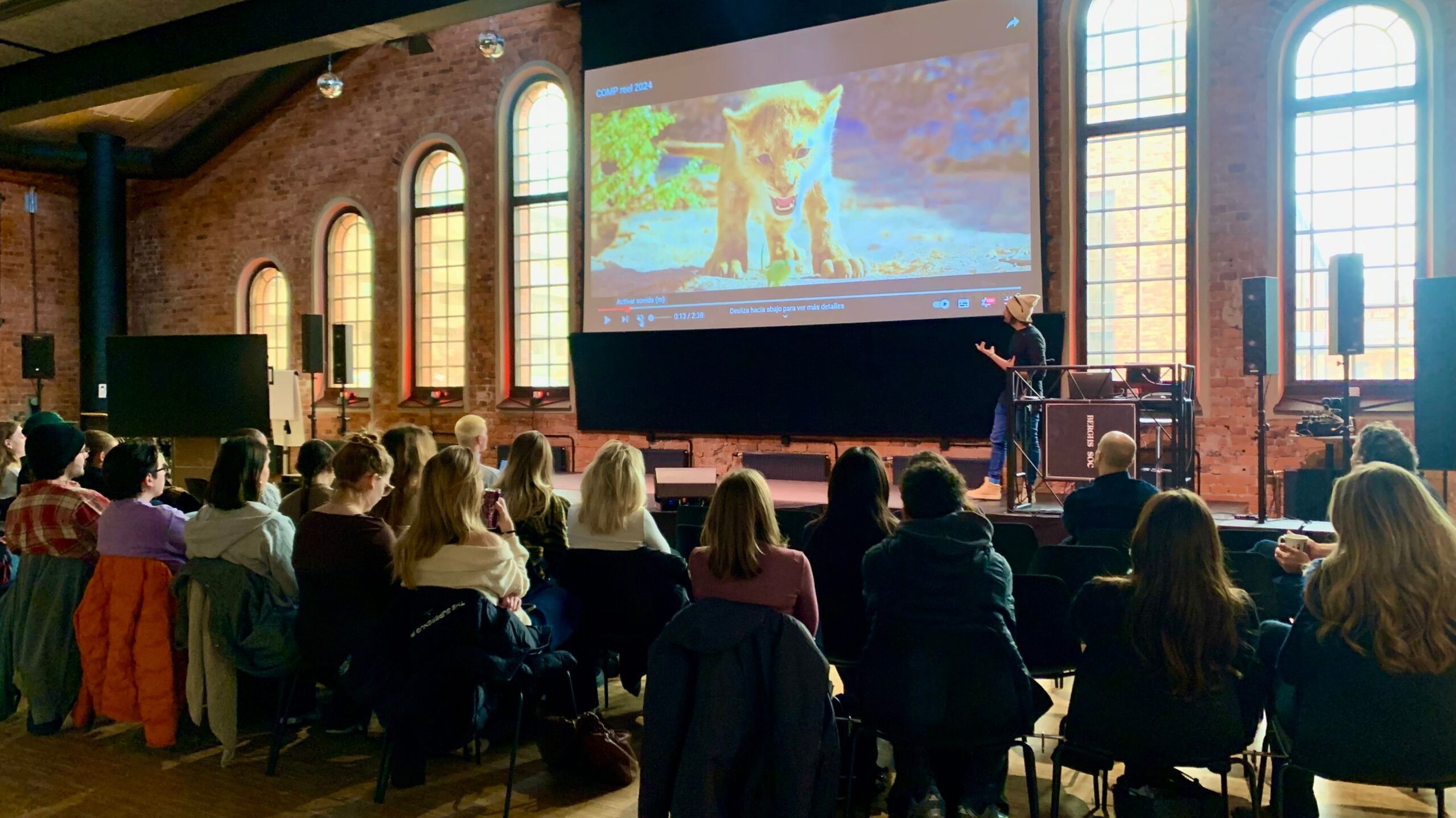 A group of students sitting in Berghs auditorium listening to guest lecturer Josep Antoni Ribas Rosello talking about video effects. Computer generated scene from the movie "Lion King" in the background.
