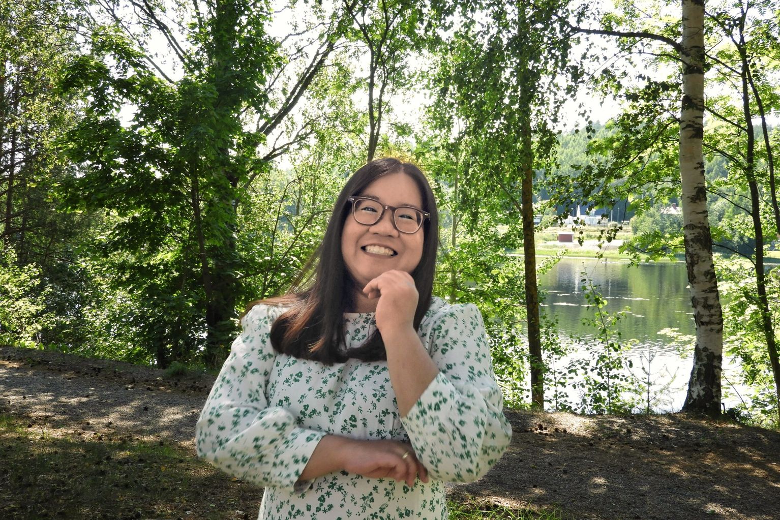 Jit-Aree stands in the wood surrounded by greenery, smiling at the camera.
