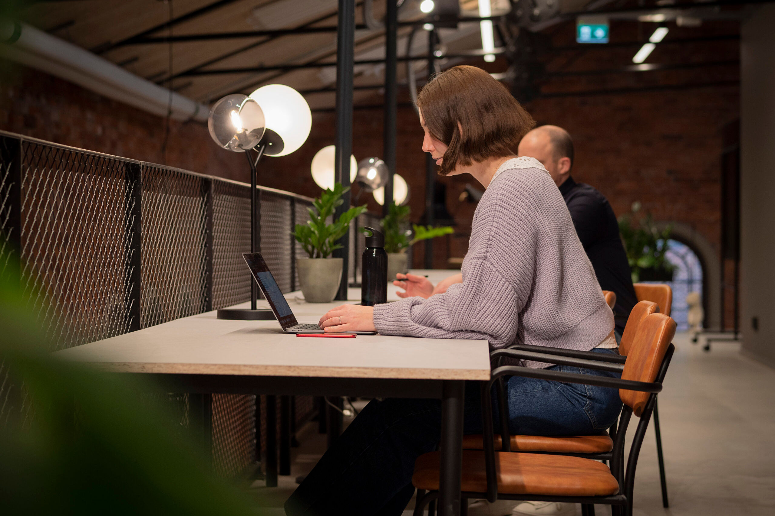 Ett footografi av två personer som sitter och arbetar vid sina datorer i vår mysiga miljö på Berghs.