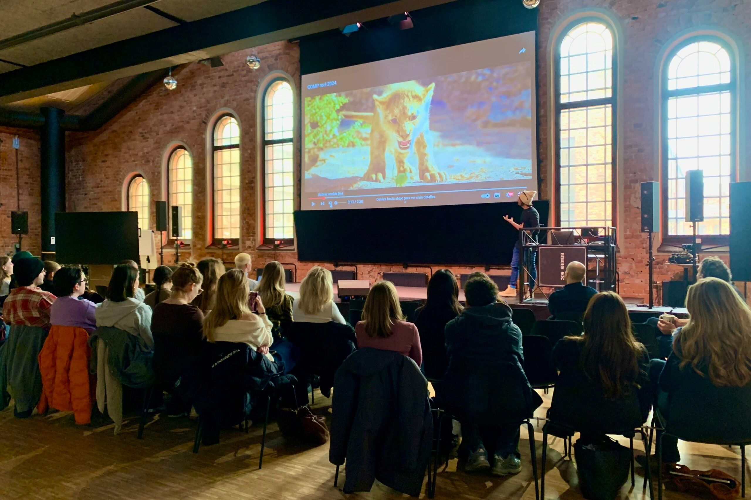 A group of students sitting in Berghs auditorium listening to guest lecturer Josep Antoni Ribas Rosello talking about video effects. Computer generated scene from the movie "Lion King" in the background.