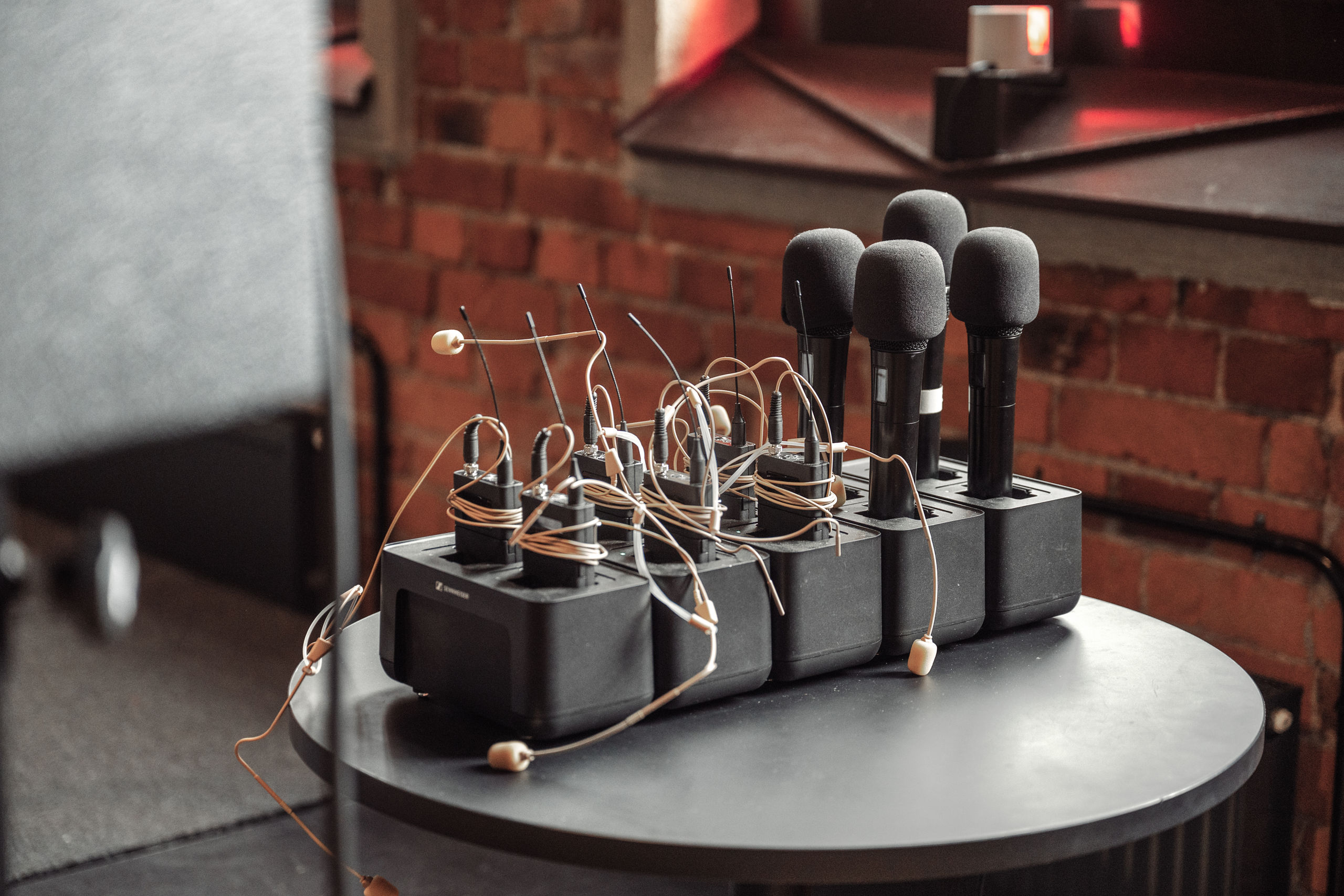 Bild på mikrofoner och mikrofonmyggor i ett stativ på ett runt bord. I bakgrunden anar man en tegelvägg och en scen.