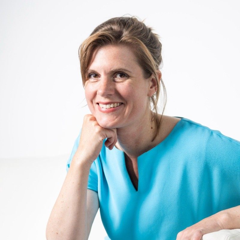 A portrait image of Wiebke Apitzsch in a light blue blouse, smiling at the camera.