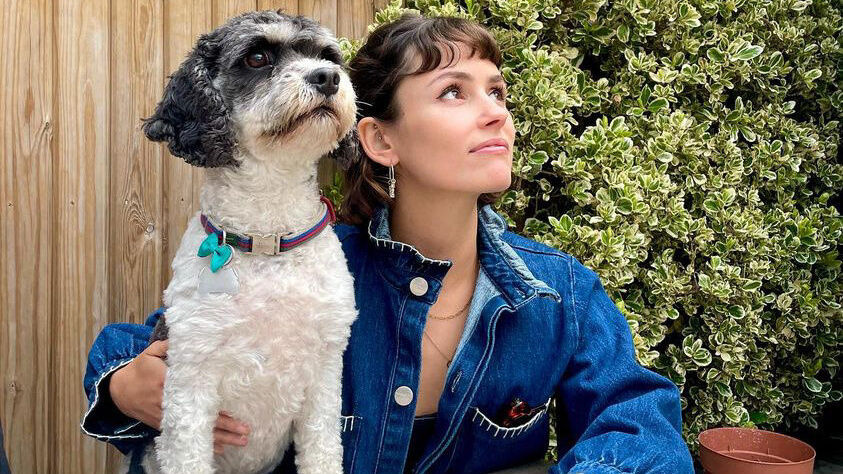 Flo Cussans with her puppy, sitting by a table looking up at the sky.