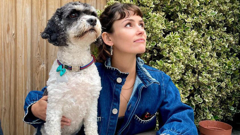 Flo Cussans with her puppy, sitting by a table looking up at the sky.