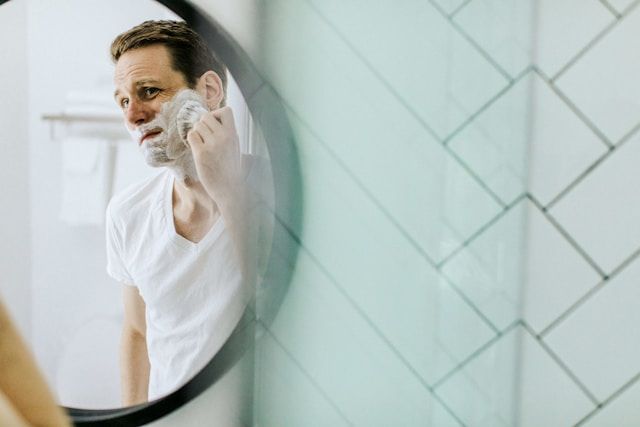 Man shaving in front of bathroom mirror