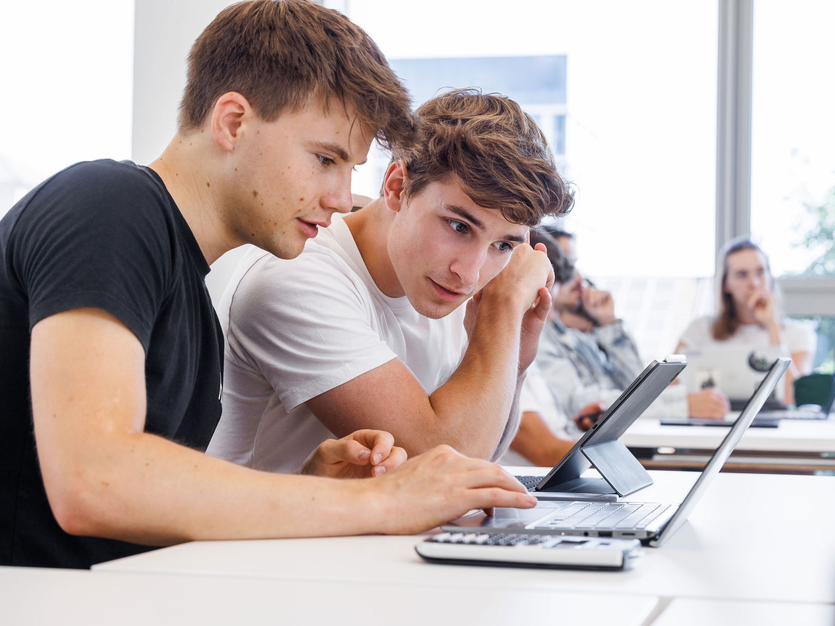 Two students looking into a laptop