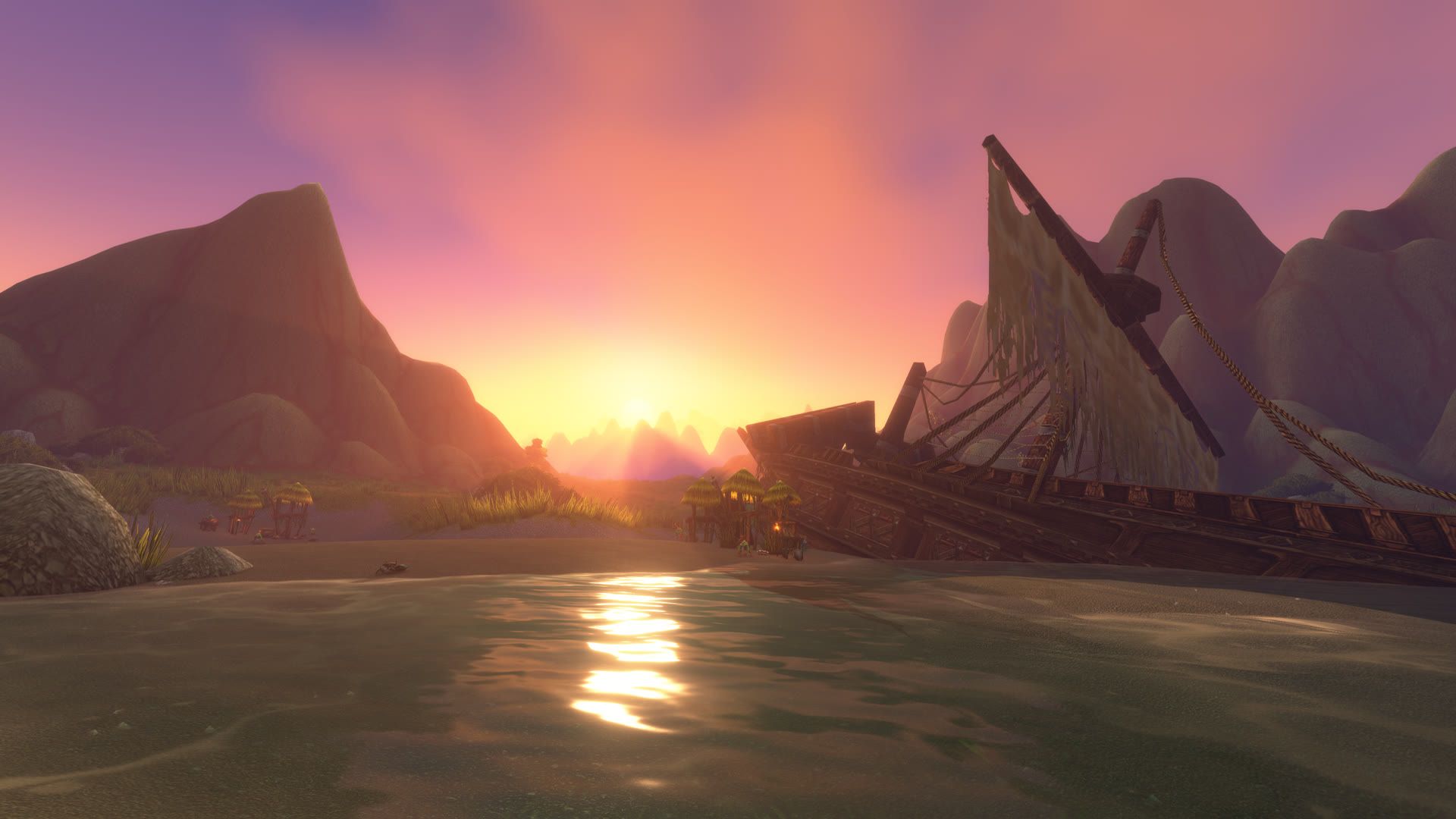 Sunrise over shallow water, a wrecked sailing ship half-buried on the shore and cliffs rising behind it.