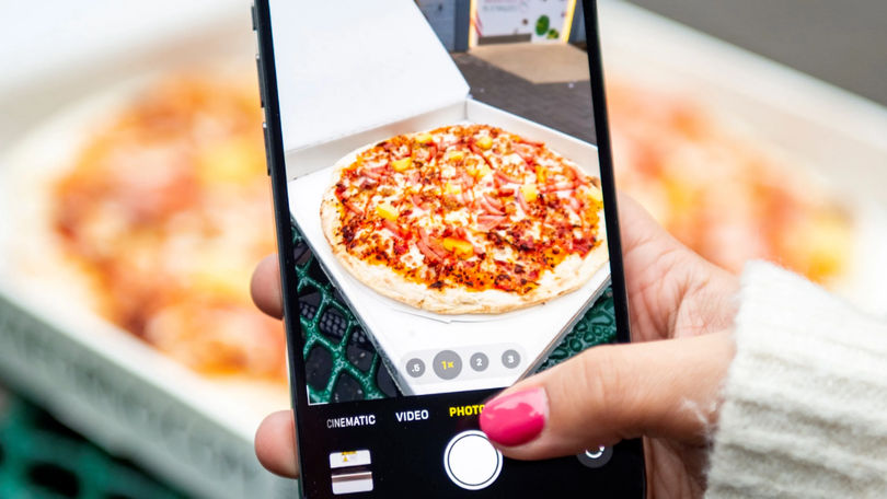A phone taking a photo of the Pizzaforno hawaiian pizza