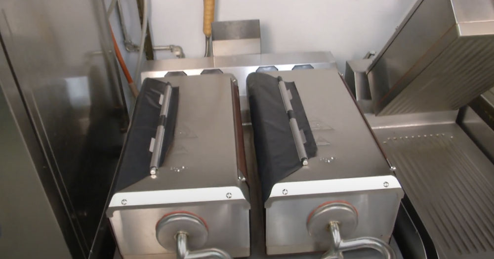 Taylor® double-sided grill with Teflon release sheets reinstalled snug on both upper platens after cleaning.