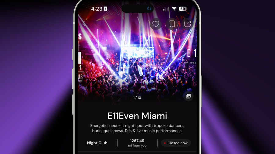 A vibrant nightclub scene at E11Even Miami, featuring energetic crowds illuminated by colorful lights and lasers, with performers on stage, under a neon atmosphere.