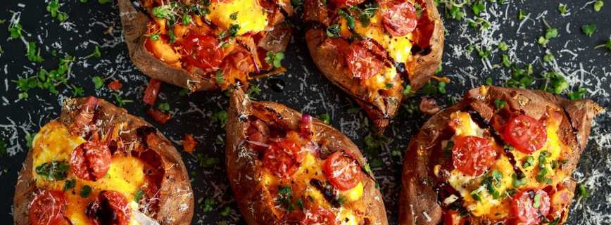 Overhead shot of five weed baked stuffed potatoes With lots of tomatoes and Parmesan cheese sprinkled over top of them