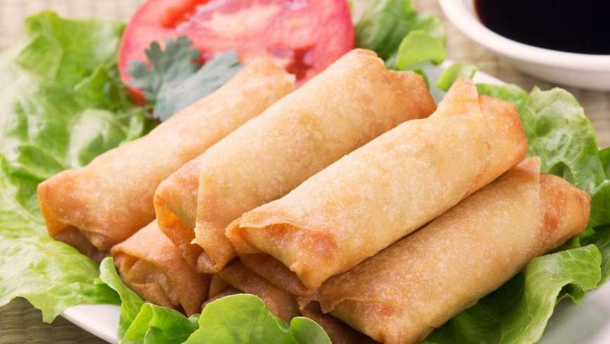 Six weed spring rolls on a piece of lettuce and tomato on a white plate