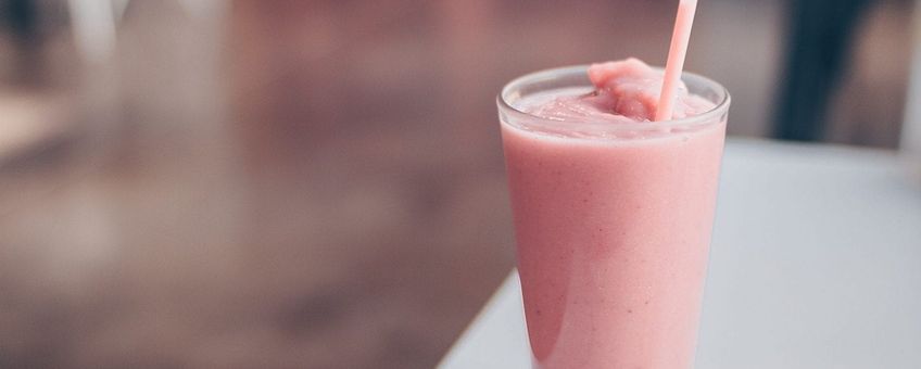 Edible strawberry smoothie on a white chair with brown floor in the background out of focus