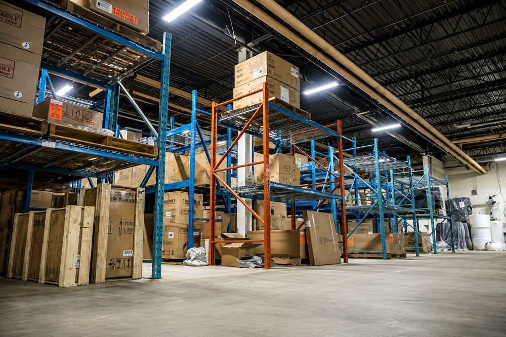 Linear LED fixtures above loaded pallet racking, where rack height and aisle layout decide light uniformity