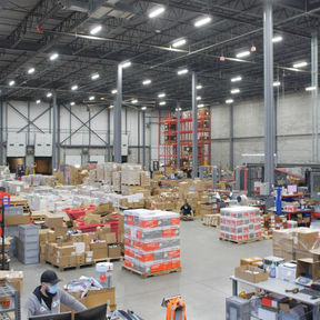 Warehouse distribution facility with inventory pallets under bright LED high-bay lighting