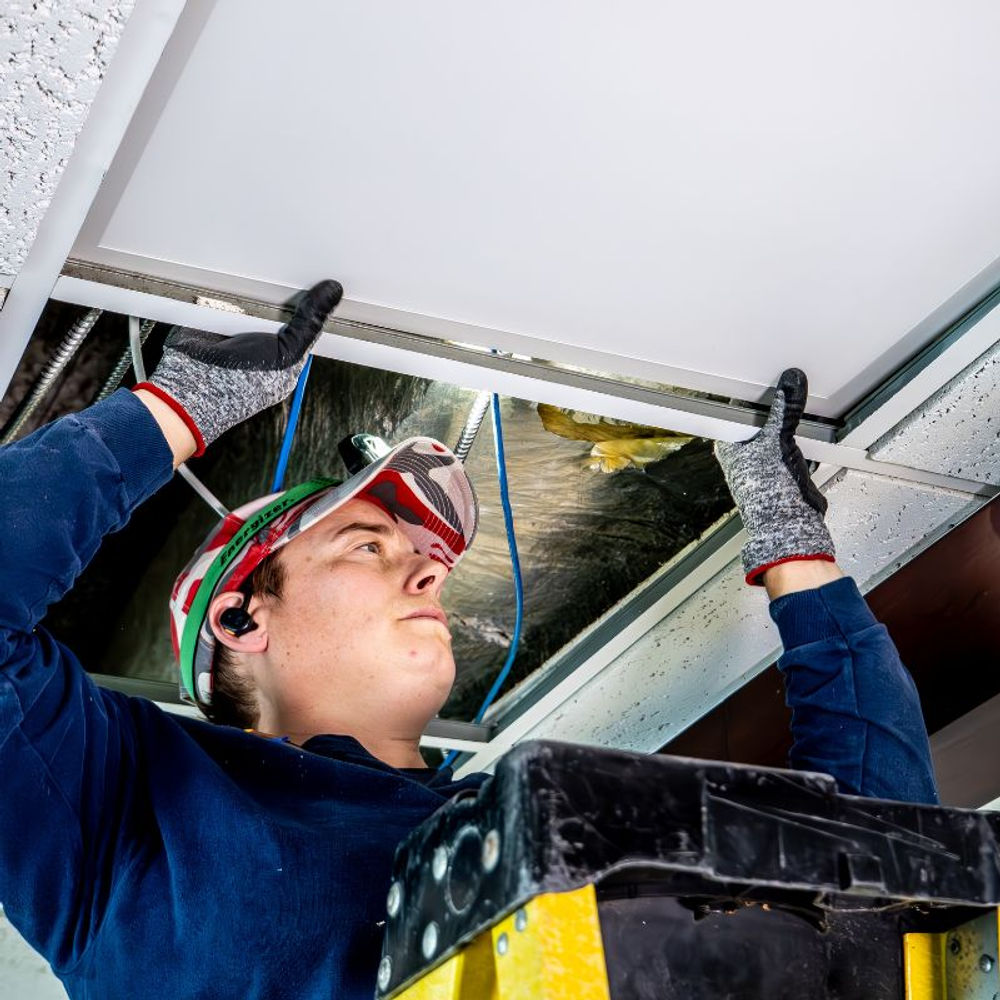 Licensed electrician installing an LED fixture during a Think Green Solutions retrofit