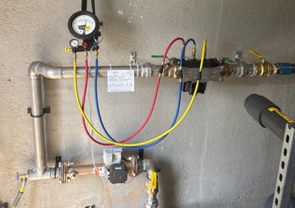 Backflow prevention assembly with test kit hoses attached during testing
