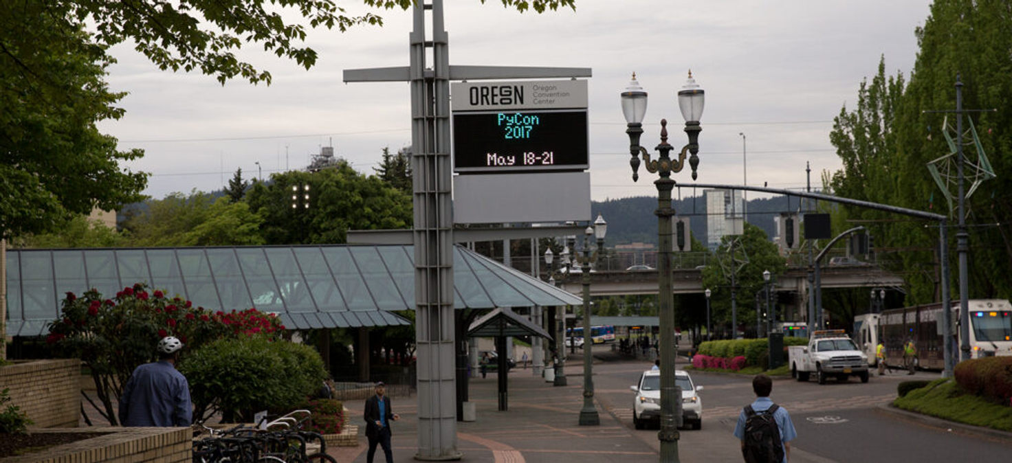 Downtown Portland street bustling with cars and a bus during PyCon 2017