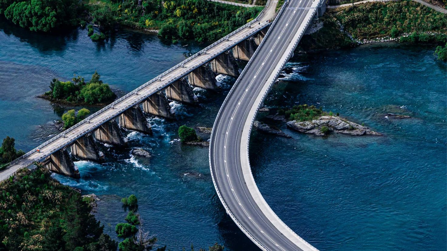Aerial view of a bridge splitting over water, representing multi-gateway payment routing, failover strategy, and redundant checkout infrastructure for SaaS subscription billing.