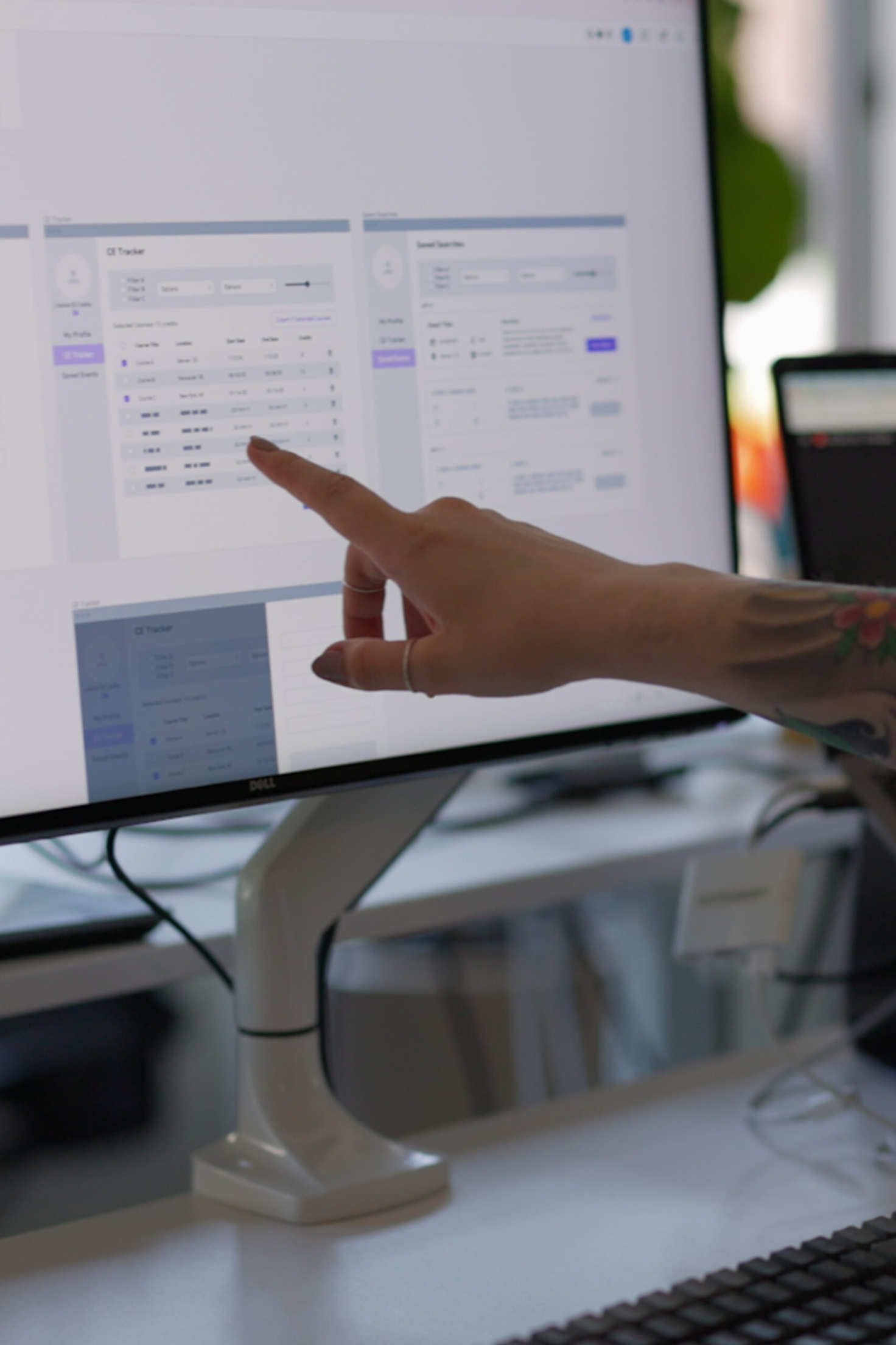 A UX designer at Cuttlesoft reviews high-fidelity wireframes on a large display, pointing out key interface elements during the design review process. The screen shows detailed mockups with careful attention to layout, typography, and component spacing - essential elements of our user interface design services. This interaction demonstrates Cuttlesoft's iterative design approach, where wireframes evolve through careful review and refinement based on user research and testing. The professional monitor setup supports detailed interface work across web applications, enterprise software, and mobile app design, ensuring pixel-perfect execution of user-centered designs.