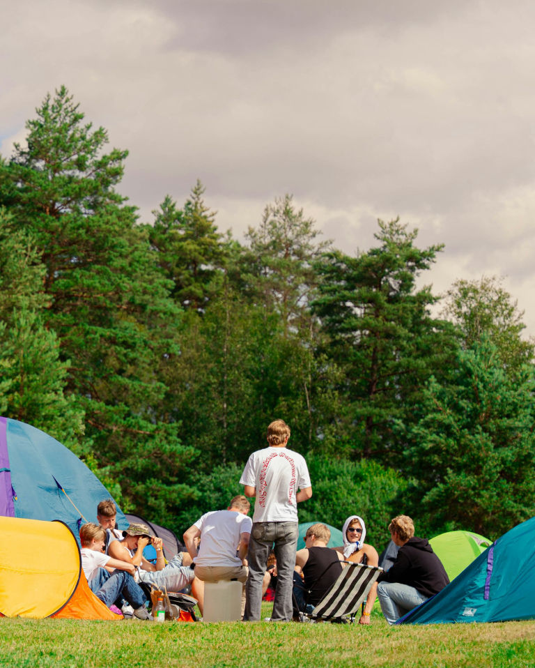 People are camping outside, gathered in a circle