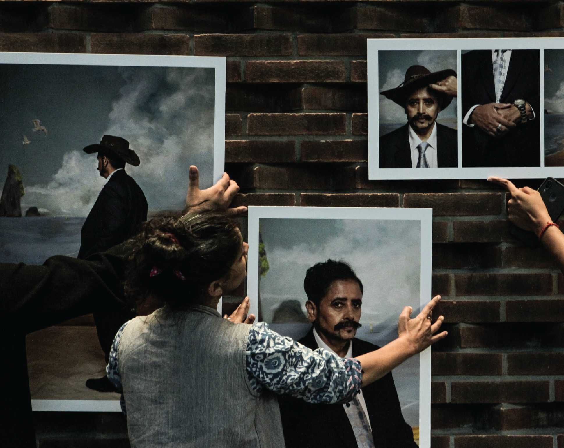 People mounting large portrait photos on a brick wall