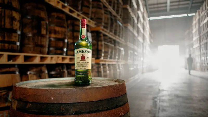 Jameson Irish Whiskey bottle amongst whiskey barrels