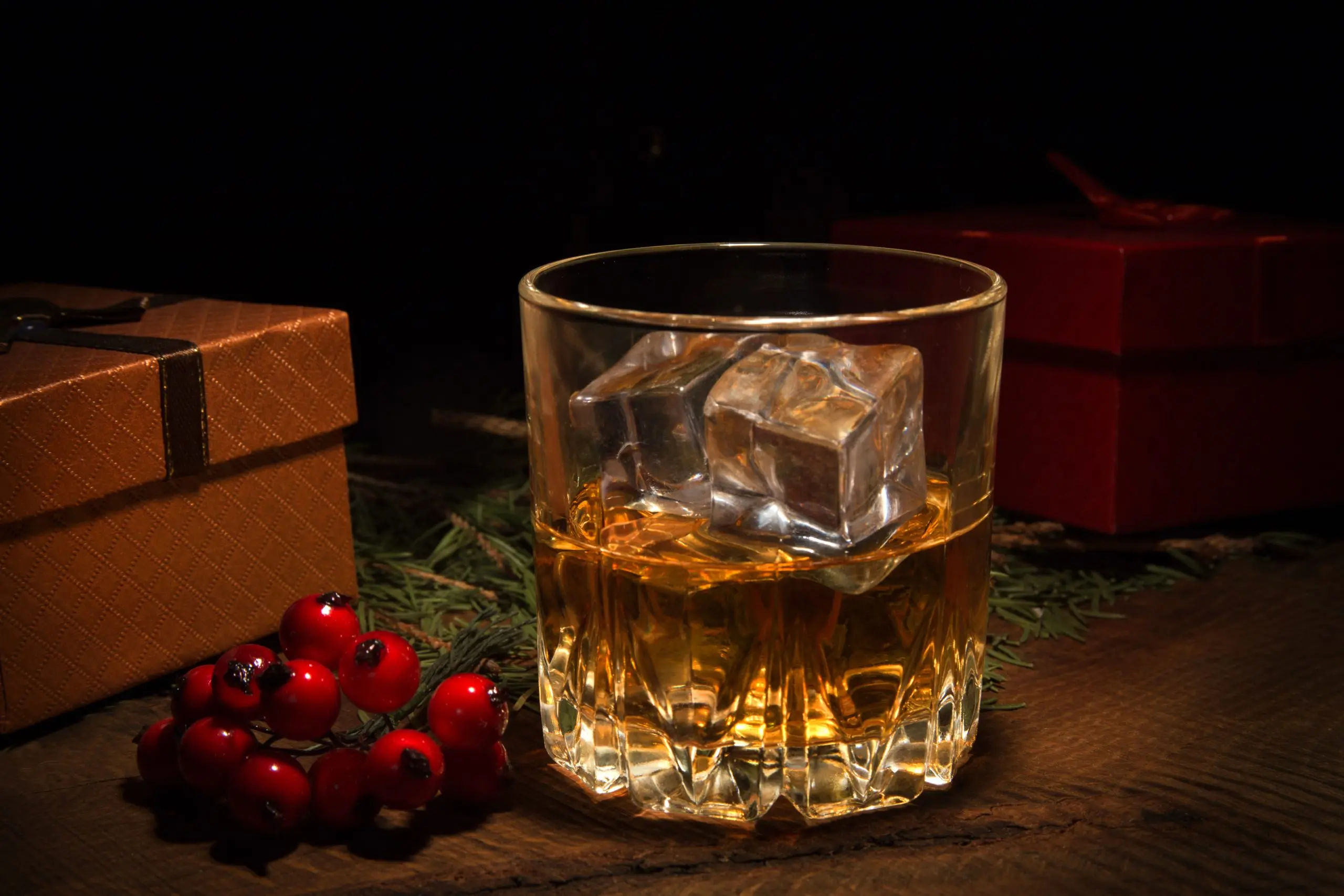 glass with cognac or whiskey, gift box and christmas balls. new year's tree. happy holidays decoration.
