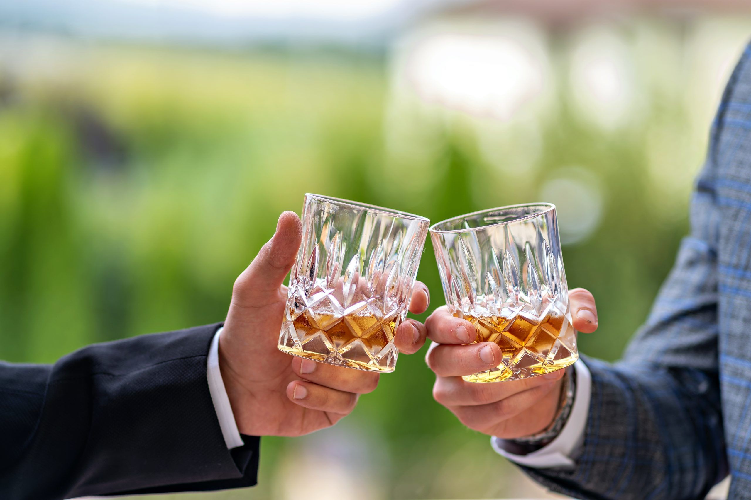 a couple of people holding up two glasses of whiskey