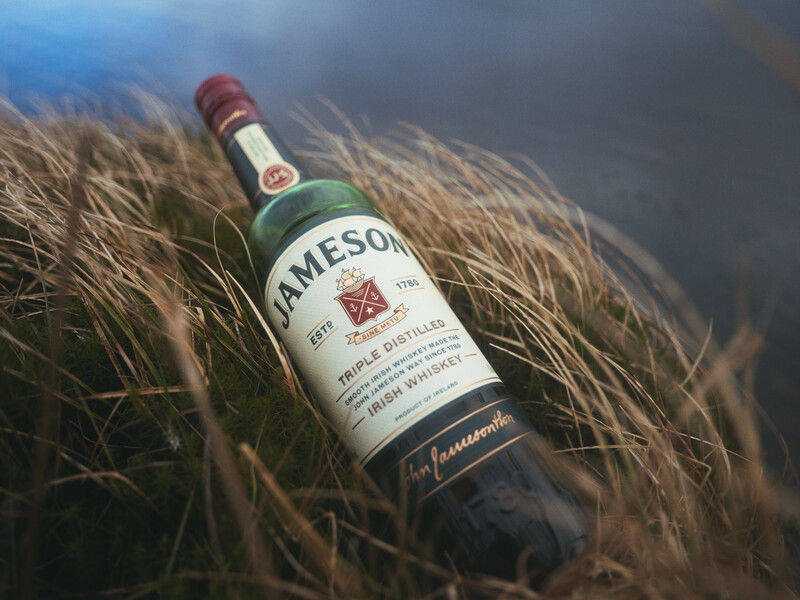 Jameson bottle in a windy field for section on what Irish whiskey is made form