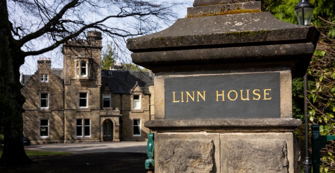 View of the entrance gates of Linn House, a grand and historic Scottish manor surrounded by well-manicured gardens.
