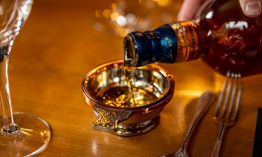 Premium whisky being poured from a bottle into an elegant receptacle.