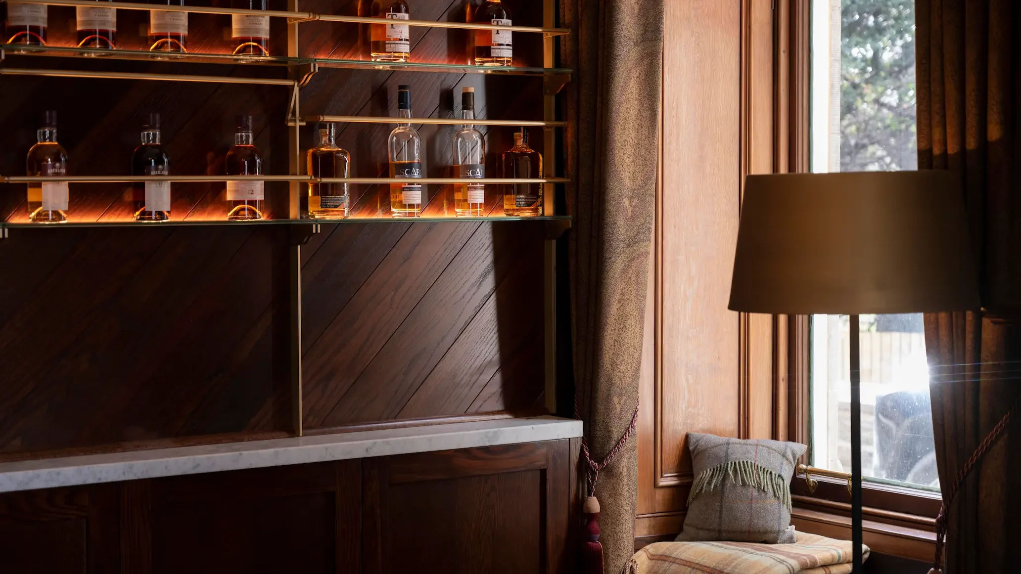 Softly lit whisky bottles on shelves against dark wooden panelling.
