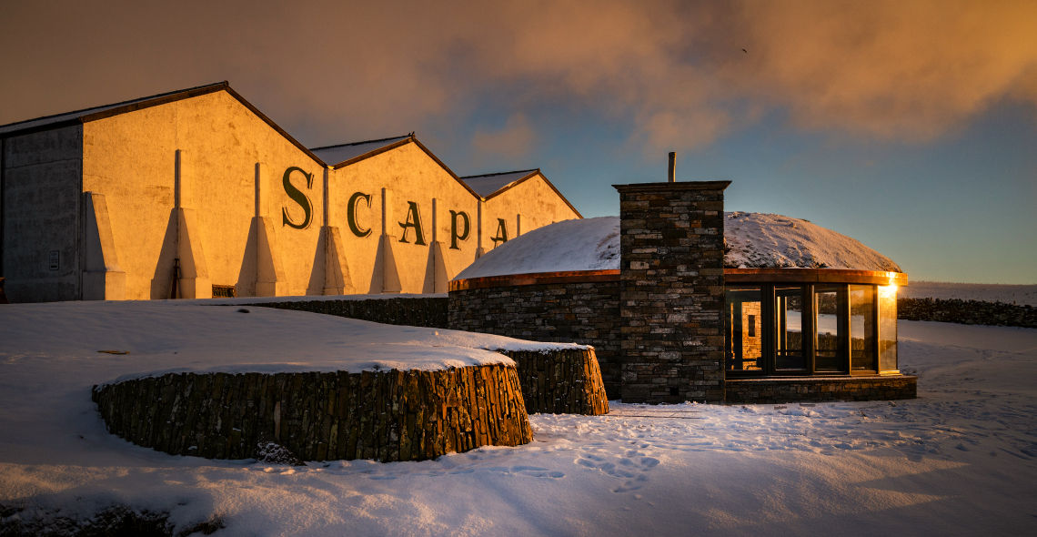 The Scapa distillery at sunset in the snow.