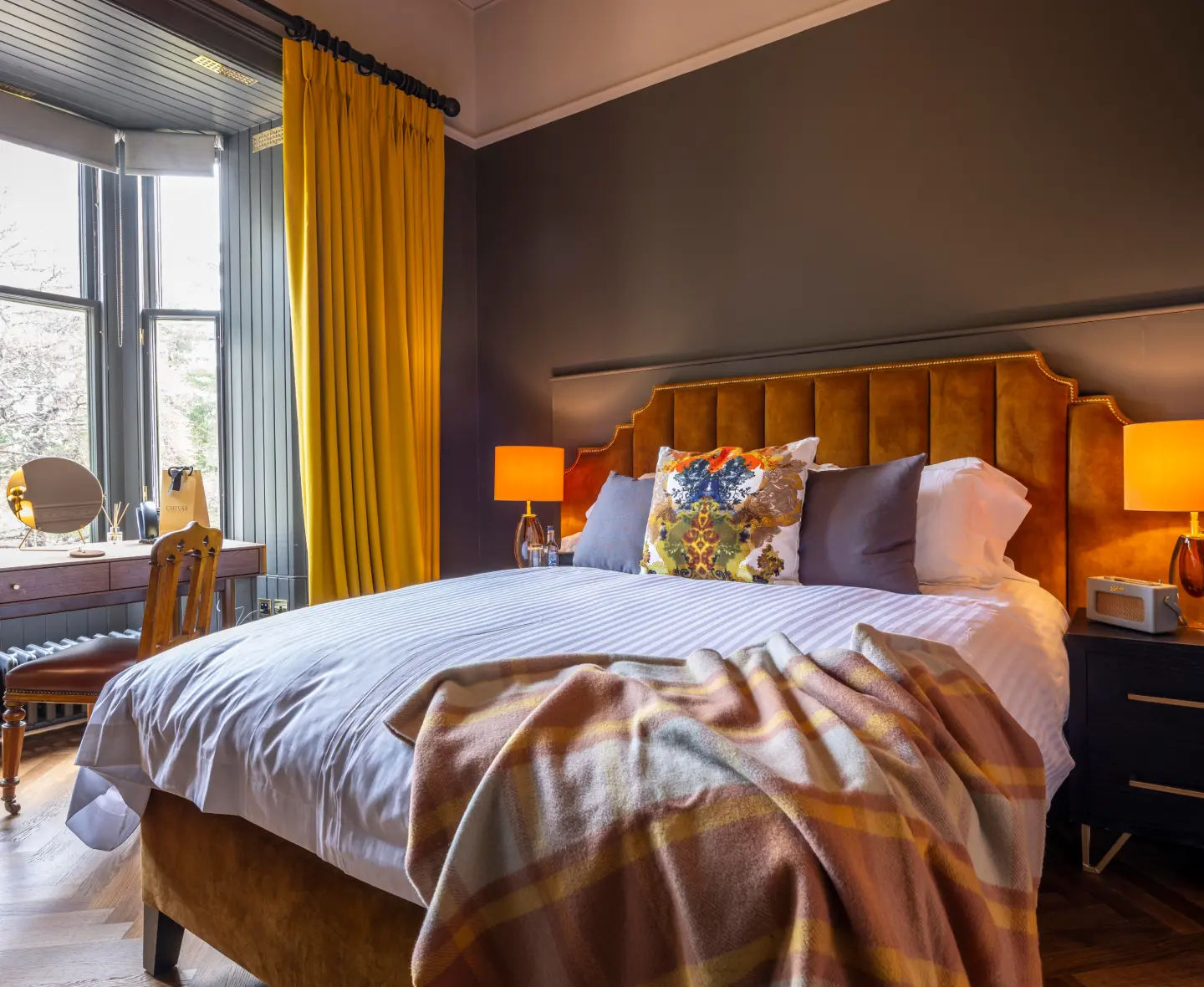 Elegant Allt-a-Bhainne bedroom with warm toned furnishings and bright natural light from a large bay window.