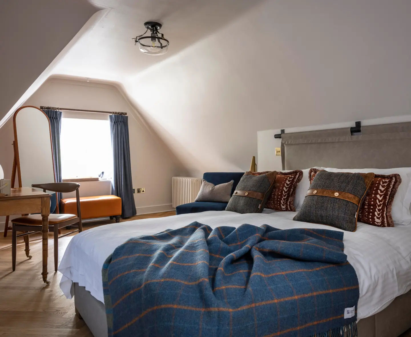 Elegant Braeval bedroom featuring a king-size bed, luxury bedding, patterned cushions and a large window.