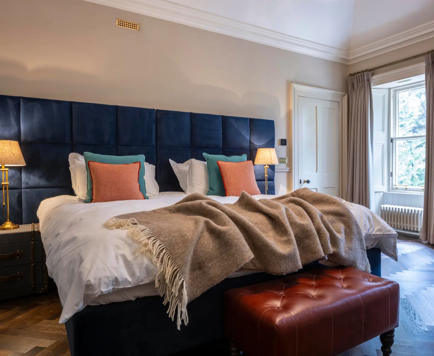Inviting Glenburgie bedroom with a large bed, elegant blue and white bedding and bright, natural light from large windows.