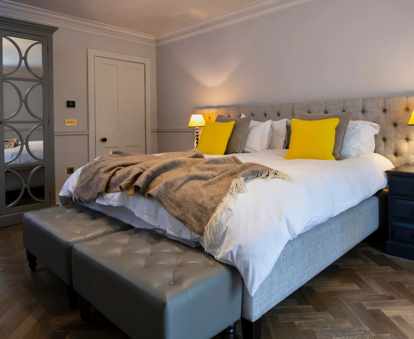 The neutral-toned Glentauchers bedroom with an elegant grey bed and yellow cushions.