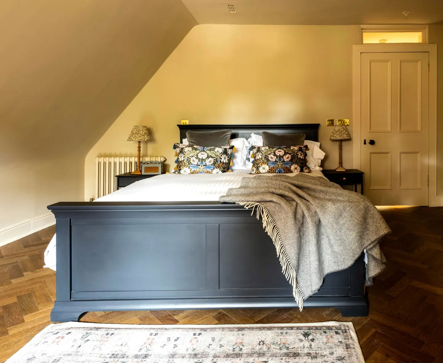 Chic Miltonduff bedroom featuring neutral toned bedding, patterned cushions, stylish bedside lamps and warm natural light.
