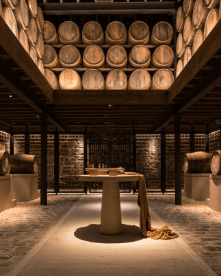 Stylishly lit distillery warehouse with a gallery of whisky barrels.