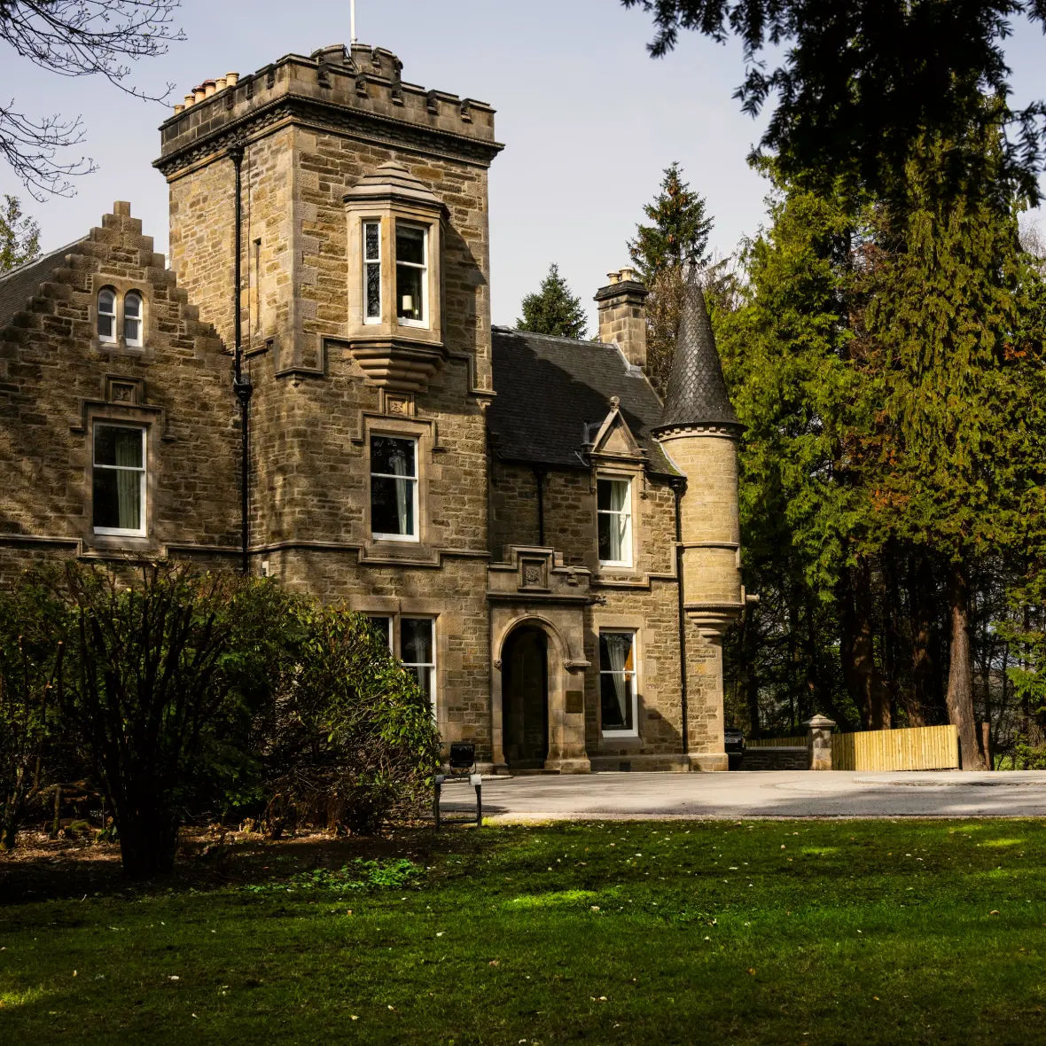 Exterior view of Linn House, showcasing its elegant architecture surrounded by lush greenery. The grand facade and well-manicured grounds highlight the luxurious ambiance of the property.