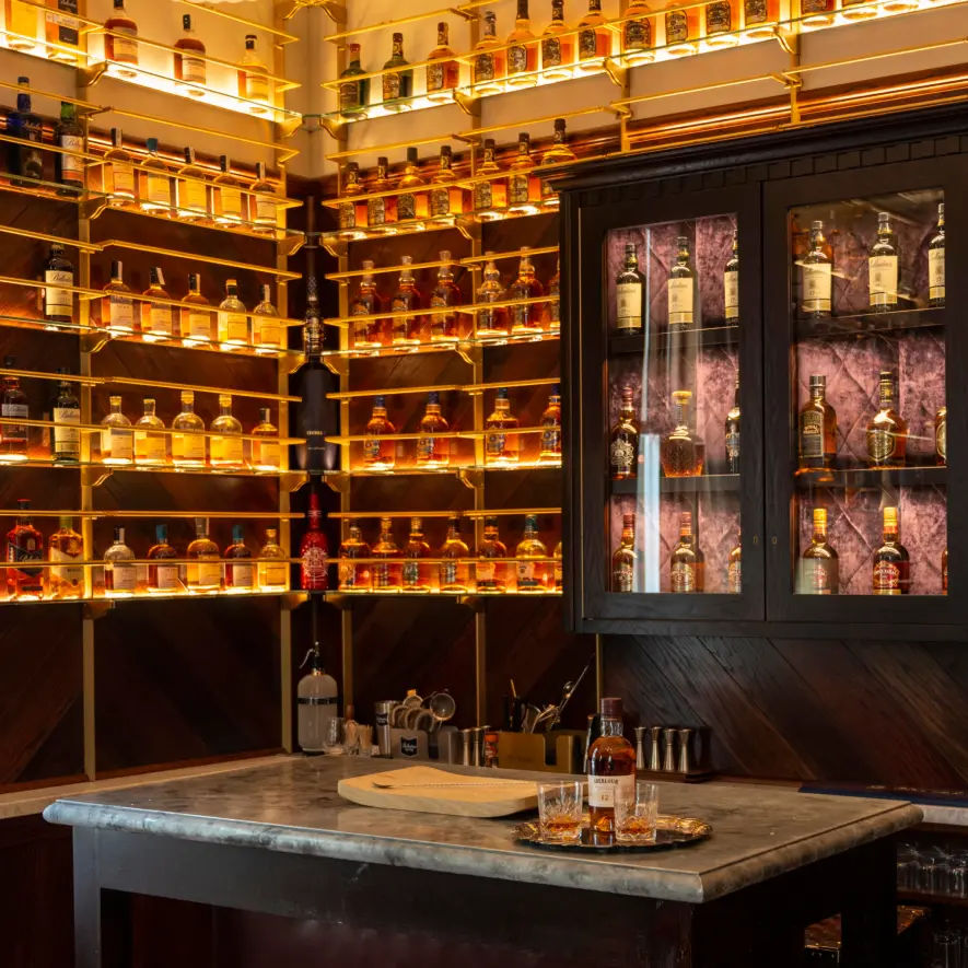 Stylish whisky room featuring shelves of back-lit whisky bottles, and warm ambient lighting.