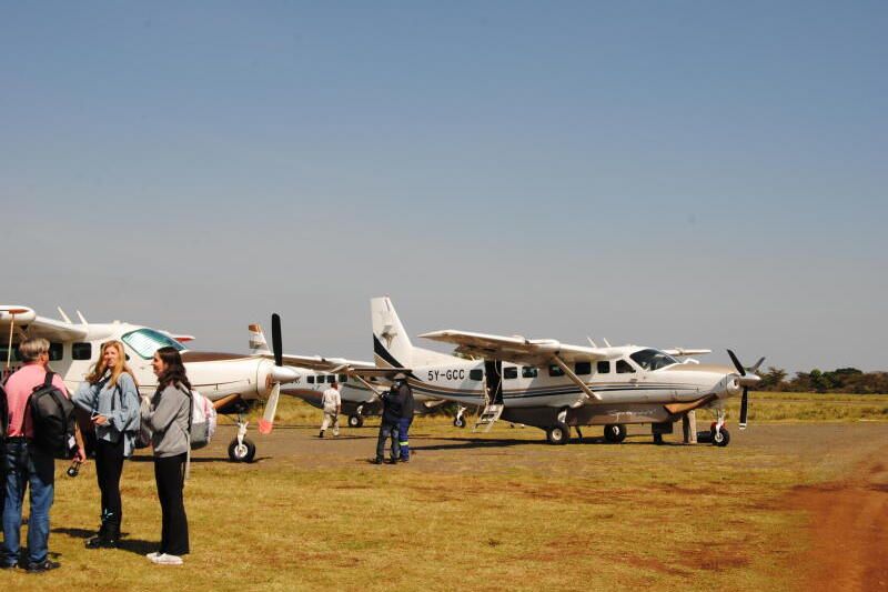 Safari guest standing at the Masai Mara airstrip in Kenya before a scenic flight
