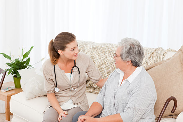 A registered nurse provides skilled nursing care in the home of an elderly female patient.